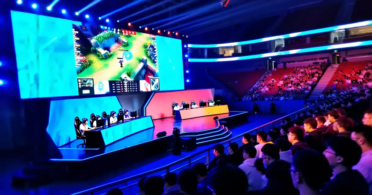 Packed esports arena with competitors on stage and audience in stands