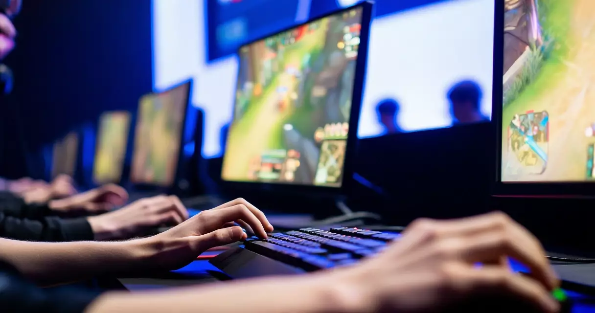 Esports players competing at a tournament stage with keyboards and gaming monitors