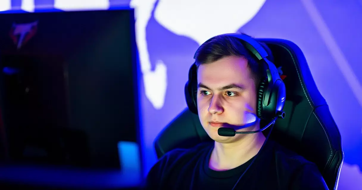 Esports player wearing a gaming headset at a lit competition booth