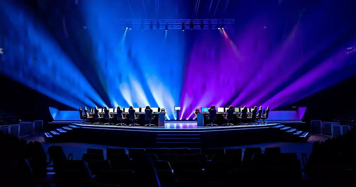 Empty esports tournament stage with gaming setups under stage lighting