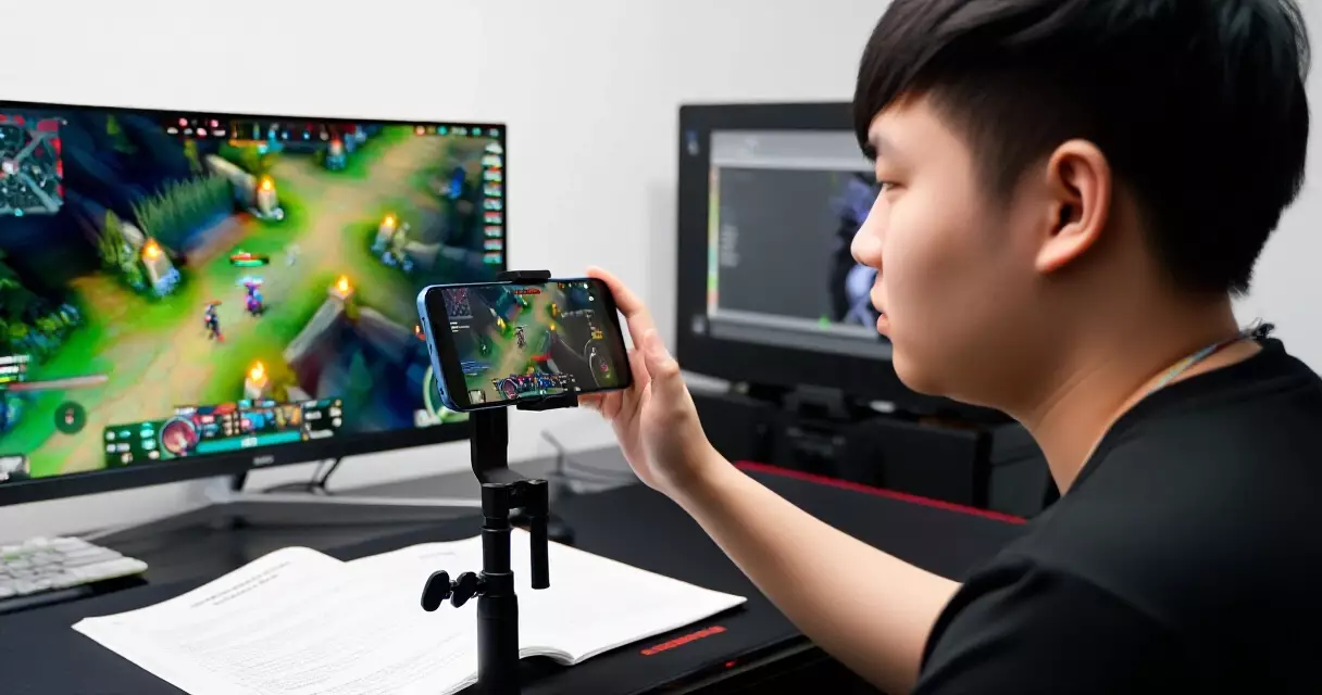 Pro mobile esports player reviewing training footage on smartphone and monitor