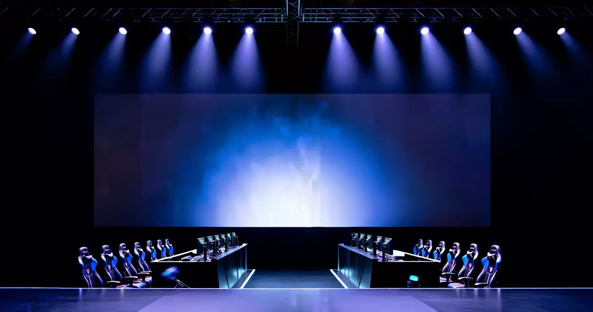 Empty esports tournament stage with overhead spotlights and gaming stations
