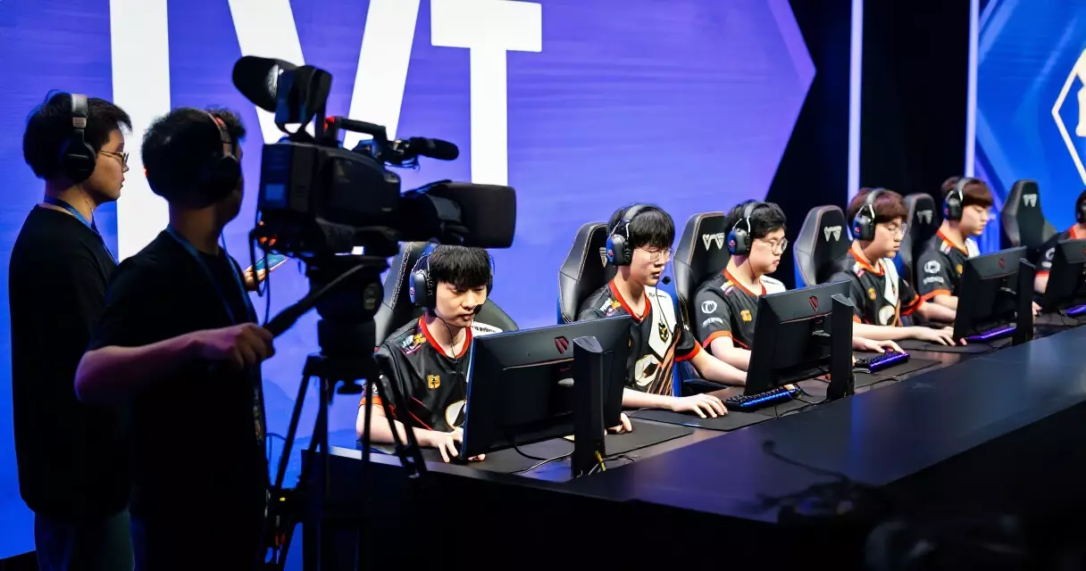 Esports players on stage with broadcast camera crew filming the live competition