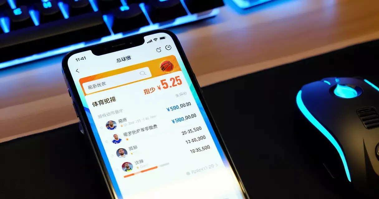 Smartphone with a betting app on a desk next to a gaming keyboard