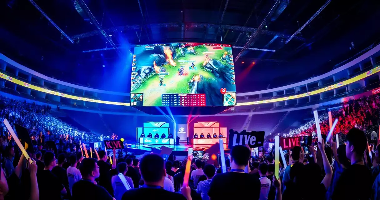 Packed esports arena during a live tournament with large LED screens showing gameplay